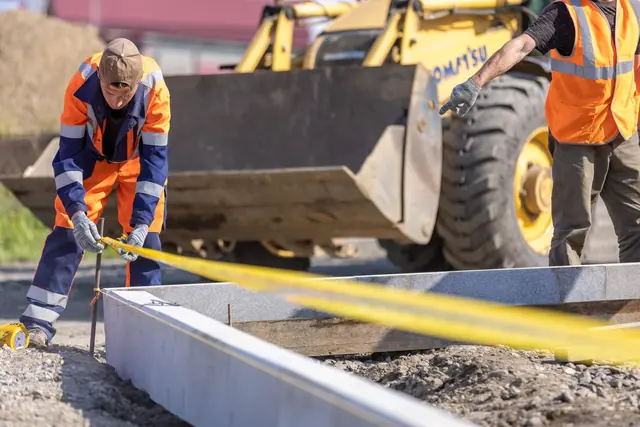 Şantiye alanında şerit metre ile ölçüm yapan işçiler