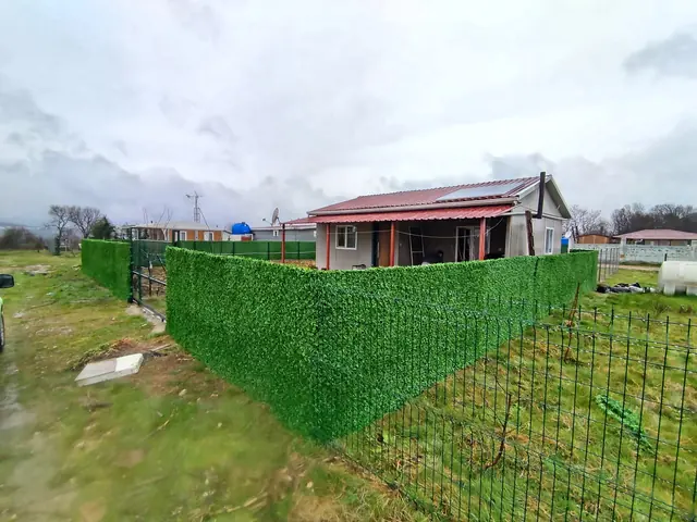 Arsa sınırı boyunca uzanan panel çit hattı ve bir bölümüne geçirilmiş çim çit